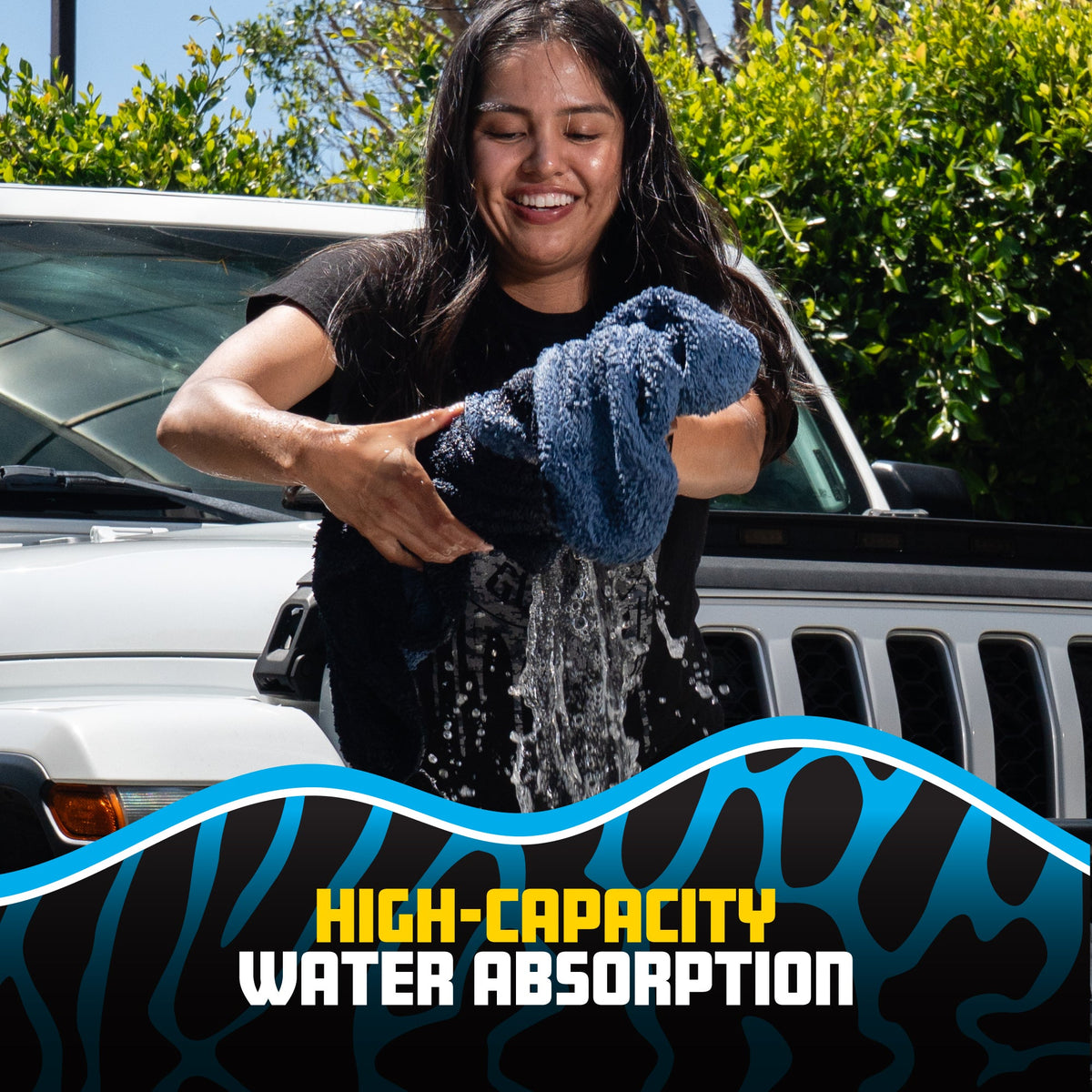 A woman outdoors stands beside a white vehicle, holding and pouring water over a dark blue microfiber towel to demonstrate its high water absorption. A graphic overlay at the bottom reads 'HIGH-CAPACITY WATER ABSORPTION' with a blue and black patterned background.