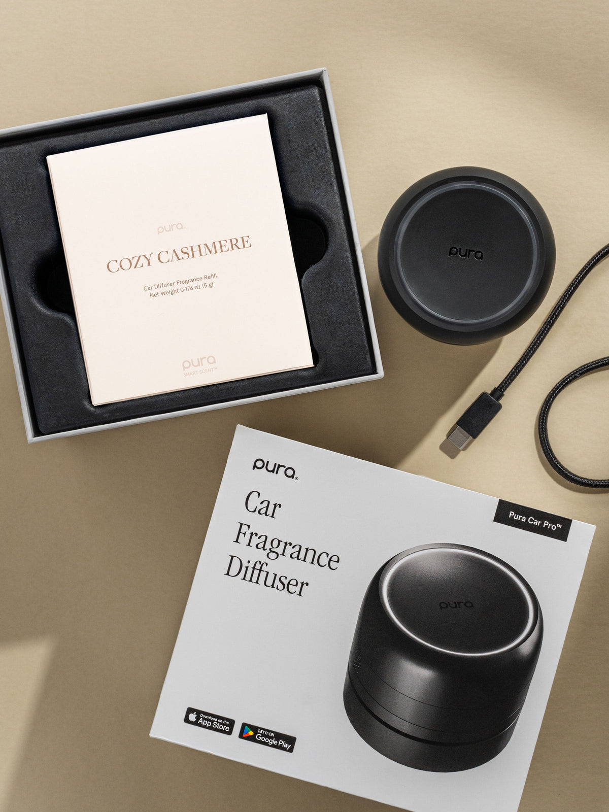 Pura Car Pro diffuser, Cozy Cashmere car fragrance, and packaging on a beige background